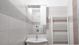 a white bathroom with a sink and a mirror at miniSZILVA Apartman in Balatonalmádi