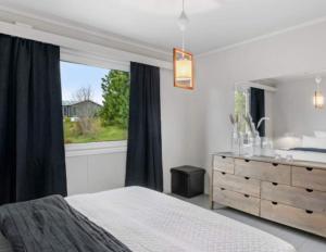 a bedroom with a bed and a window and a dresser at Tranquil Haven Villa in Ålesund
