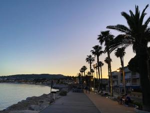 a beach with palm trees and a boardwalk next to the water at CASA BLUE sur une jolie place proche du vieux port by LaConciergerie13 in La Ciotat