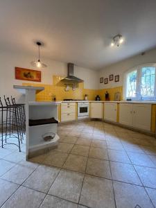 eine große Küche mit weißen Schränken und Fliesenboden in der Unterkunft Villa provençale 8 personnes in Ventabren