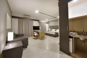 a hotel room with a bed and a living room at Araucaria Plaza in Ribeirão Preto