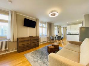 ein Wohnzimmer mit einem Sofa und einer Küche in der Unterkunft Amaroo - Apartments Potsdam “Brandenburger Tor” in Potsdam