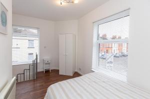 a white bedroom with a bed and a large window at 33 Stanley Road in Northampton