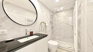 ein weißes Badezimmer mit Waschbecken und Spiegel in der Unterkunft Viva Riviera Brand New Top Floor close Croisette in Cannes + 4 Fotos