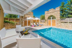 a swimming pool with white chairs and a house at Villa Lefki Sofita in Makris Gialos