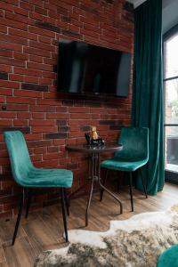 a brick wall with a table and two chairs and a tv at Restored Factory Residence - 55m2, Top Location - by Rentujemy in Łódź