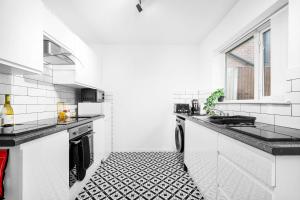 a white kitchen with a black and white tile floor at Luxury 4 Bedroom Bungalow - Parking - Sutton Coldfield 75C in Birmingham