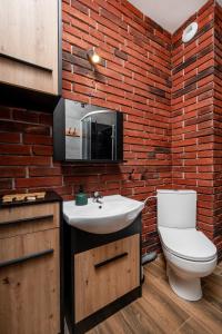 La salle de bains est pourvue d'un lavabo blanc et d'un mur en briques. dans l'établissement Restored Factory Residence - 55m2, Top Location - by Rentujemy, à Łódź