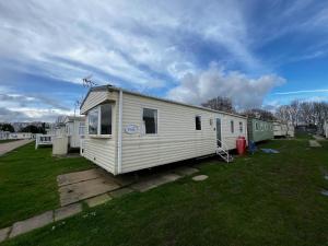 a small white trailer parked in a yard at Lovely 8 Berth Caravan At Highfield Grange In Essex Ref 26213o in Clacton-on-Sea