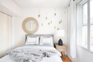 a white bedroom with a bed and a mirror at 11-4F Prime west village designer 1BR in New York