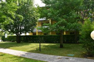 un edificio giallo con alberi di fronte di Simona's Home a Desenzano del Garda