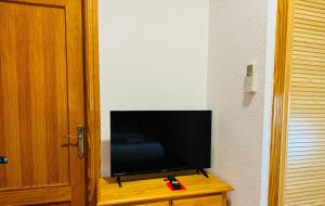 telewizor z płaskim ekranem siedzący na drewnianym stole w obiekcie Ballestar Hotel Bar & Grill w mieście Barajas de Melo