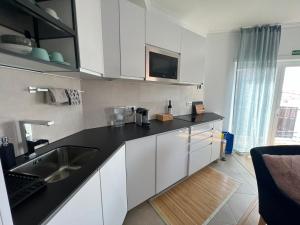 uma cozinha com armários brancos e um lavatório em Nazare Oasis Suites and Retreats na Nazaré