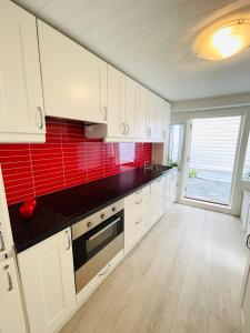 a kitchen with white cabinets and a red tile wall at Central Economic Stavanger Kongsteinsgata in Stavanger