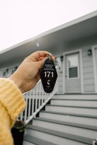 a person holding a house keychain in front of a house at Auberge sur Mer in Notre-Dame-du-Portage