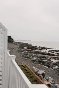 a white fence next to a beach with the ocean at Auberge sur Mer in Notre-Dame-du-Portage