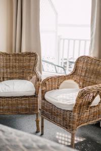- deux chaises en osier assises dans une pièce avec fenêtre dans l'établissement Auberge sur Mer, à Notre-Dame-du-Portage