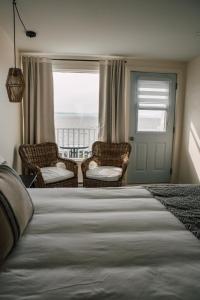 a bedroom with two chairs and a bed and a window at Auberge sur Mer in Notre-Dame-du-Portage