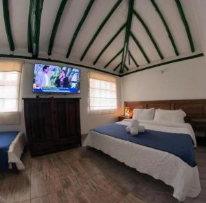 Schlafzimmer mit einem Bett und einem Flachbild-TV in der Unterkunft hotel abahunza in Villa de Leyva