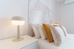 a white bedroom with a bed with pillows and a lamp at Casa Arai en Casco Histórico con Parking Gratuito in Ronda