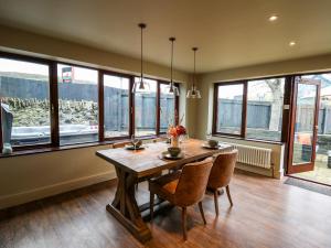 a dining room with a table and chairs and windows at Dant Y Llew in Bow Street