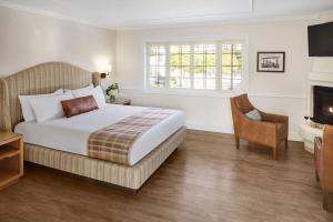 een slaapkamer met een bed en een stoel en een open haard bij Coachman's Inn, A Four Sisters Inn in Carmel +45 foto's