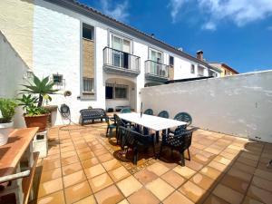 patio ze stołem i krzesłami oraz białą ścianą w obiekcie Casa Cony w mieście Tarifa