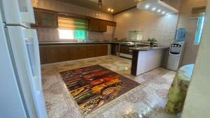 cocina con nevera y alfombra en el suelo en فيلا في الطبيعة في عجلون, en Ajloun