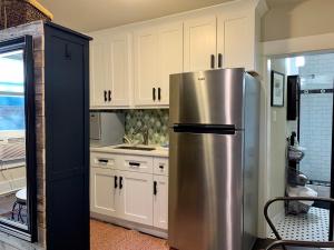 a stainless steel refrigerator in a kitchen with white cabinets at The Chic Guest Retreat in Old Town near CSU! in Fort Collins