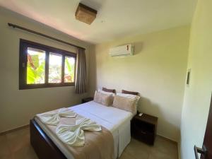 1 dormitorio con 1 cama con sábanas blancas y ventana en Pipa Beleza Melhores Aparts en Pipa