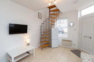 a living room with a spiral staircase and a tv at 33 Stanley Road in Northampton