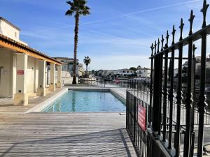 una piscina con una valla y una palmera en Quai Saint Louis - maeva Home - Villa 4 pieces 6 personnes - Prestige 544, en Aigues-Mortes