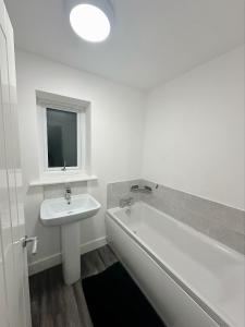 a white bathroom with a sink and a bath tub at Beautiful home in Ince-in-Makerfield
