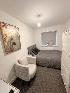 a bedroom with a bed and a white chair at Beautiful home in Ince-in-Makerfield