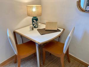 een tafel met twee stoelen en een lamp en een tafel met een laptop bij Studio Le Terra - Petit déjeuner inclus 1ère nuit - AUX 4 LOGIS in Foix