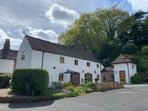 a white house with a black roof on a street at Stable Cottage in Tettenhall