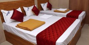 Duas camas num quarto com almofadas vermelhas e brancas em HoteL Namaste London Terminal-2 em Mumbai