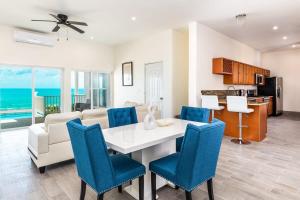 a living room with a white table and blue chairs at Breathtaking Turtle Tail Drive Oceanfront Villa in Providenciales