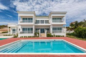 a house with a swimming pool in front of it at Breathtaking Turtle Tail Drive Oceanfront Villa in Providenciales