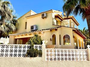 a house with a white fence and palm trees at Casa Milana in Moraira