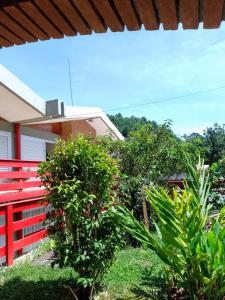 une clôture rouge devant une maison avec des plantes dans l'établissement Hospedagem Virginia Bracelli, à Campos do Jordão