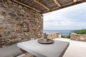 a patio with a table and a stone wall at VILLA ERIS in Agios Georgios