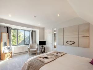 a white bedroom with a large bed and a chair at Northlands Farm - Old Farm Cottage in Chichester