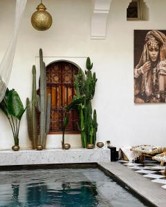 - une piscine avec des cactus et une peinture murale dans l'établissement Riad LallaBaya, à Marrakech
