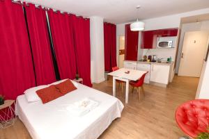トゥールーズにあるStudio rouge Ramblas Centre Toulouseの赤いカーテン、ベッド1台、テーブルが備わるベッドルーム1室が備わります。