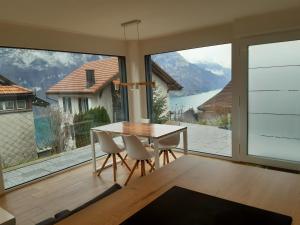 ein Esszimmer mit einem Tisch und Stühlen sowie einem großen Fenster in der Unterkunft Apartment Panorama am Walensee in Neubau-Villa in Obstalden