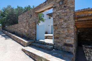 a stone building with a white door and a brick wall at VILLA ERIS in Agios Georgios