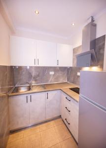 a kitchen with white cabinets and a white refrigerator at House Kohili in Nea Vrasna