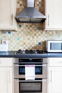 a kitchen with a stove and a microwave at Madison Hill - Bedford Hill 1 - One bedroom flat in London