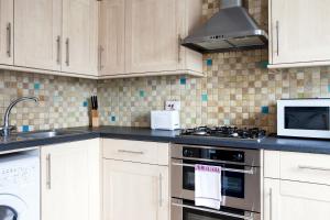 a kitchen with white cabinets and a stove top oven at Madison Hill - Bedford Hill 1 - One bedroom flat in London